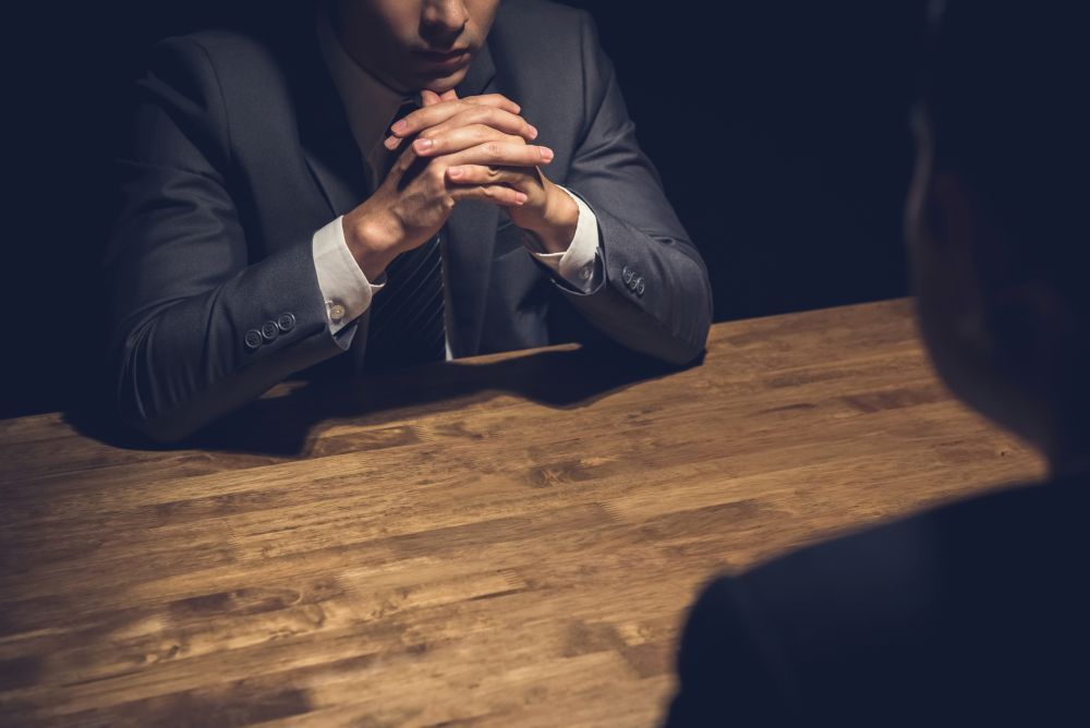 Solicitor advising a client during a Voluntary Police Interview in a formal setting with low lighting.